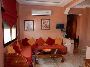 A living room with a sofa, a coffee table, and a television. - Apartment in downtown Marrakech. Everything within walking distance (Marrakesh)