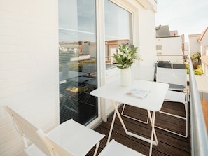A balcony with a white table, a white chair, and a potted plant. - Holiday Apartment With 2 Bedrooms (Norderney)