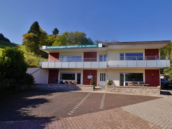 A two-story building with a balcony on the upper floor, a stone facade, and a paved entrance area. - Holiday Apartment With 1 Bedroom (Willingen)