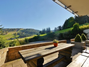 A wooden bench with a potted plant, overlooking a scenic landscape with hills and greenery. - Holiday Apartment With 1 Bedroom (Willingen)