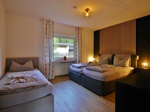 A bedroom with two beds, a window with curtains, a radiator, and a wall-mounted light fixture. - Holiday Apartment With 1 Bedroom (Willingen)