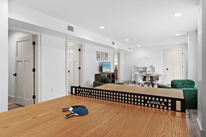 Uma sala de estar moderna com uma mesa de jantar de madeira, TV e um sofá verde.