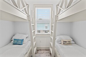 A bedroom with bunk beds, a window with blinds, and two pillows with text. - 🐾The Lookout at Betty | Heated Pool & Covered Balconies & Pet Friendly & Bikes🚲 (Santa Rosa Beach)
