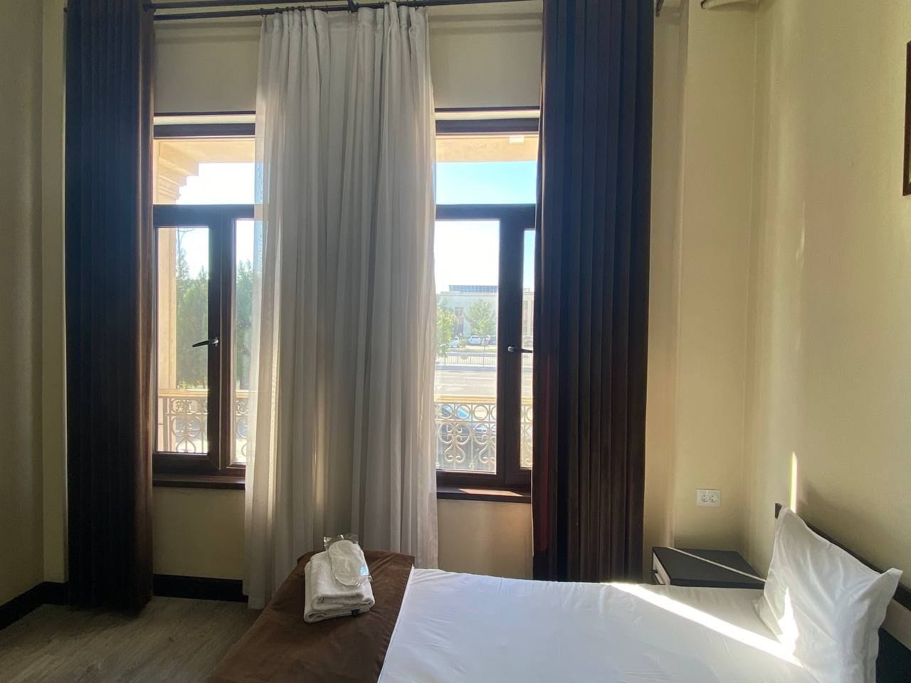 Habitación de hotel con cama, ventana con cortinas y vistas al exterior.