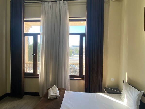 Quarto de hotel com cama, janela com cortinas e vista para o exterior.