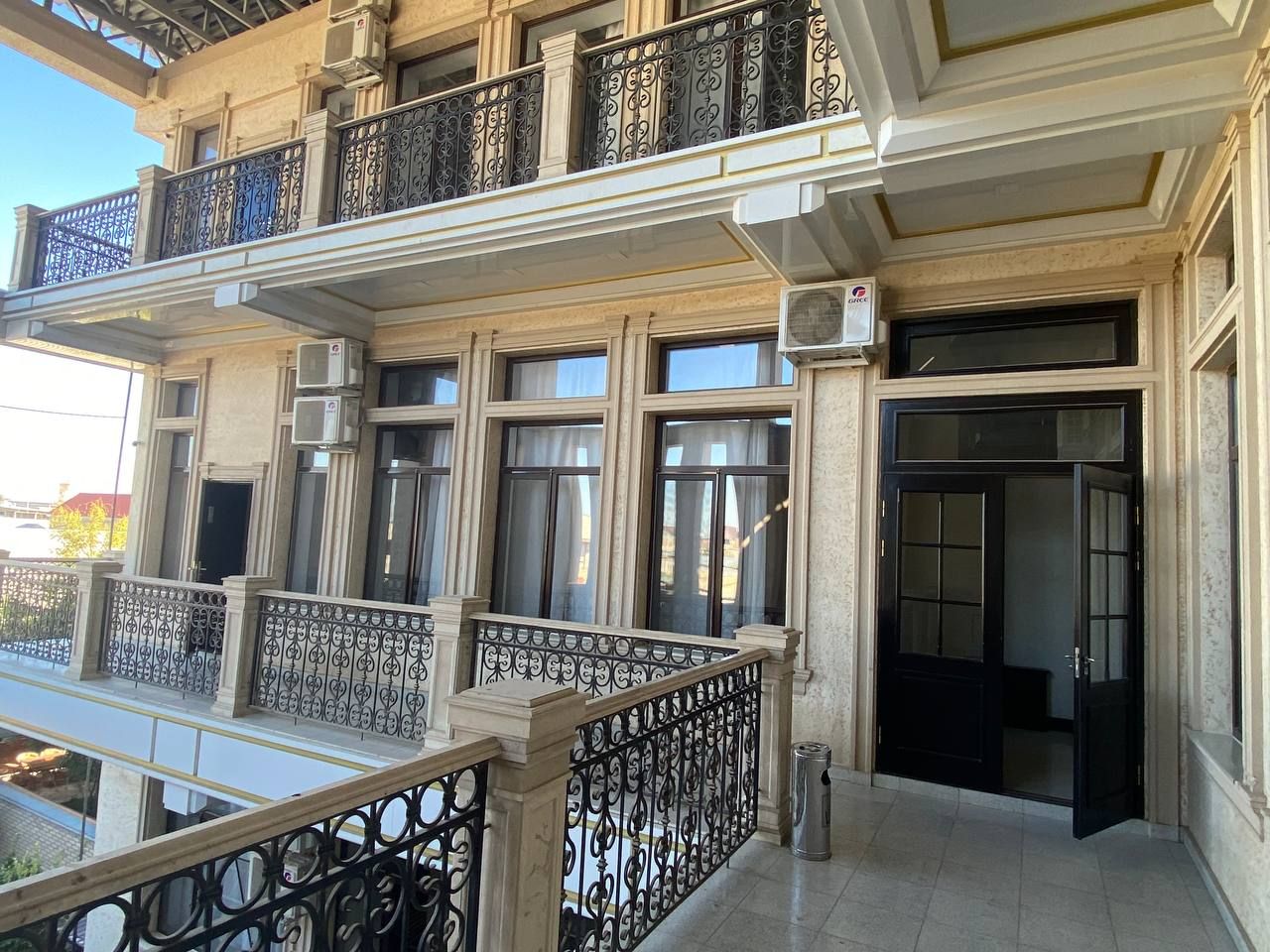 Un edificio de varios pisos con balcones, ventanas amplias y una puerta negra.