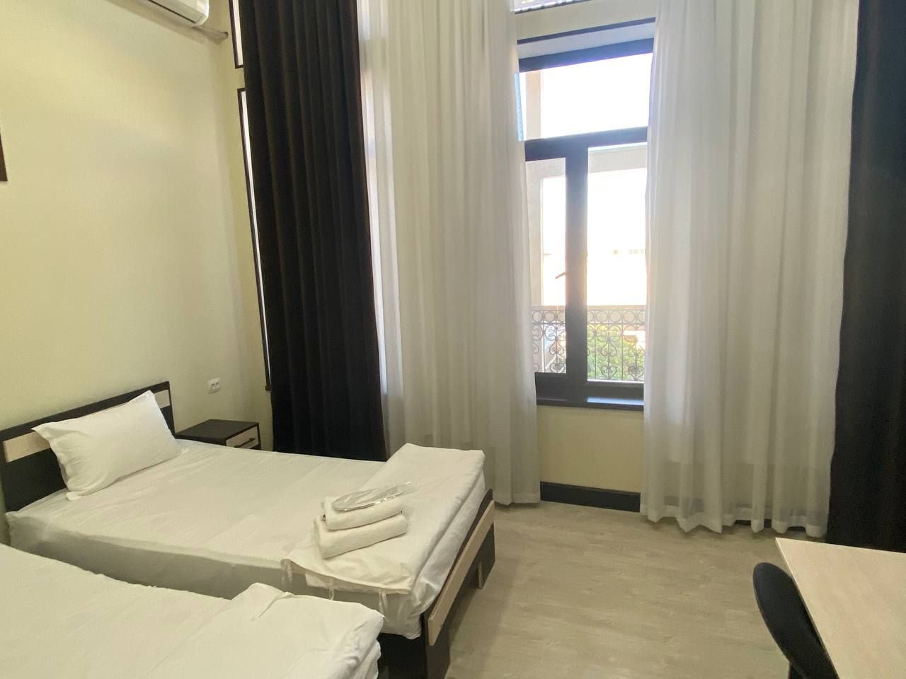 Una habitación de hotel con dos camas, una ventana con cortinas y una pequeña mesa.