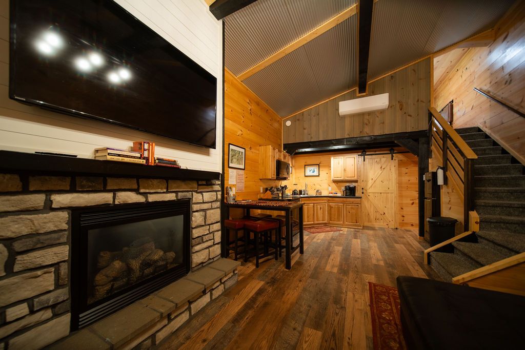 Een modern interieur met een open haard, een flatscreen-televisie, een keuken en een trap.