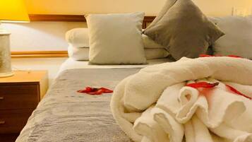 Una habitación de hotel con una cama, almohadas, una mesita de noche y una lámpara.