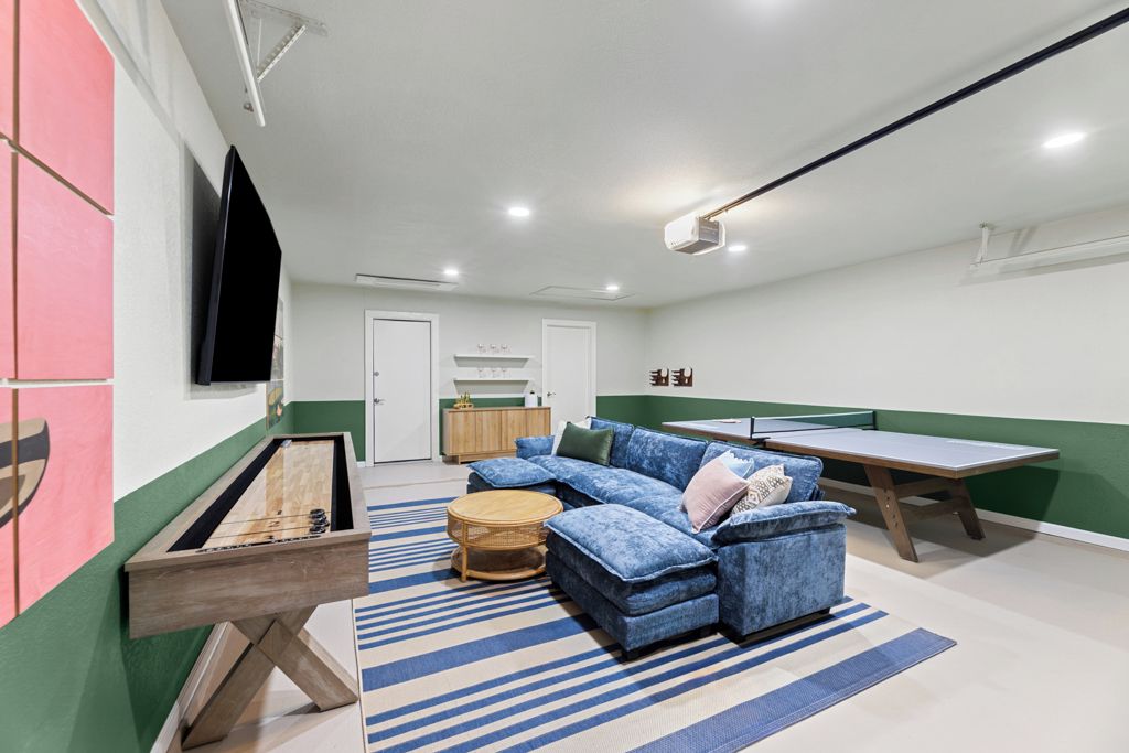 A living room with a blue sofa, a ping pong table, and a billiards table.