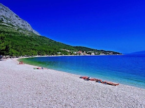 A pebble beach with clear blue waters and a mountainous backdrop. - Stone House Dalmatia Apt. 5 (Gradac)