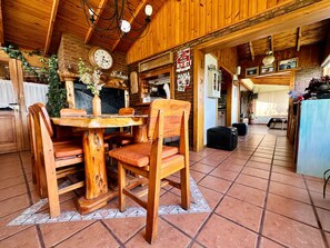 Ein rustikales Holzinterieur mit einem runden Holztisch und Stühlen, einer Uhr und einem Schild mit der Aufschrift 'Mama'.