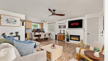 A modern living room with a fireplace, a television, and a dining area.