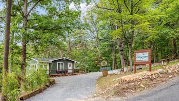 A cabin with a porch, surrounded by trees, and a sign indicating 'Vista View' and 'Panorama View Drive.'
