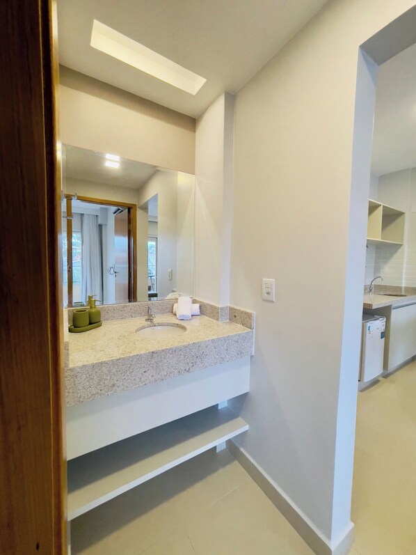 Une salle de bain moderne avec un lavabo en granit, un miroir et une étagère intégrée.