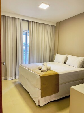 Ein Hotelzimmer mit Bett, Vorhängen und einer Tür.