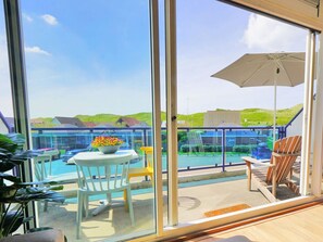 A balcony with a pool, chairs, and a table with flowers. - Seinpost 28 Callantsoog (Callantsoog)