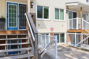 A multi-story residential building with a wooden staircase leading to a gated entrance. - Shoreline Retreat-Beach front -Cottage 1 (Wasaga Beach)