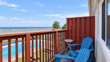 A wooden deck with a view of a swimming pool and ocean.