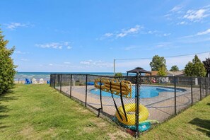 A fenced outdoor play area with a pool, slides, and a covered seating area. - Shoreline Retreat Beach Front Cottage -2 (Wasaga Beach)