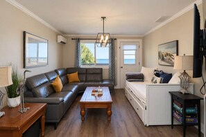 A living room with a sofa, a coffee table, a TV, and a window with a view. - Shoreline Retreat Beach Front Cottage -2 (Wasaga Beach)