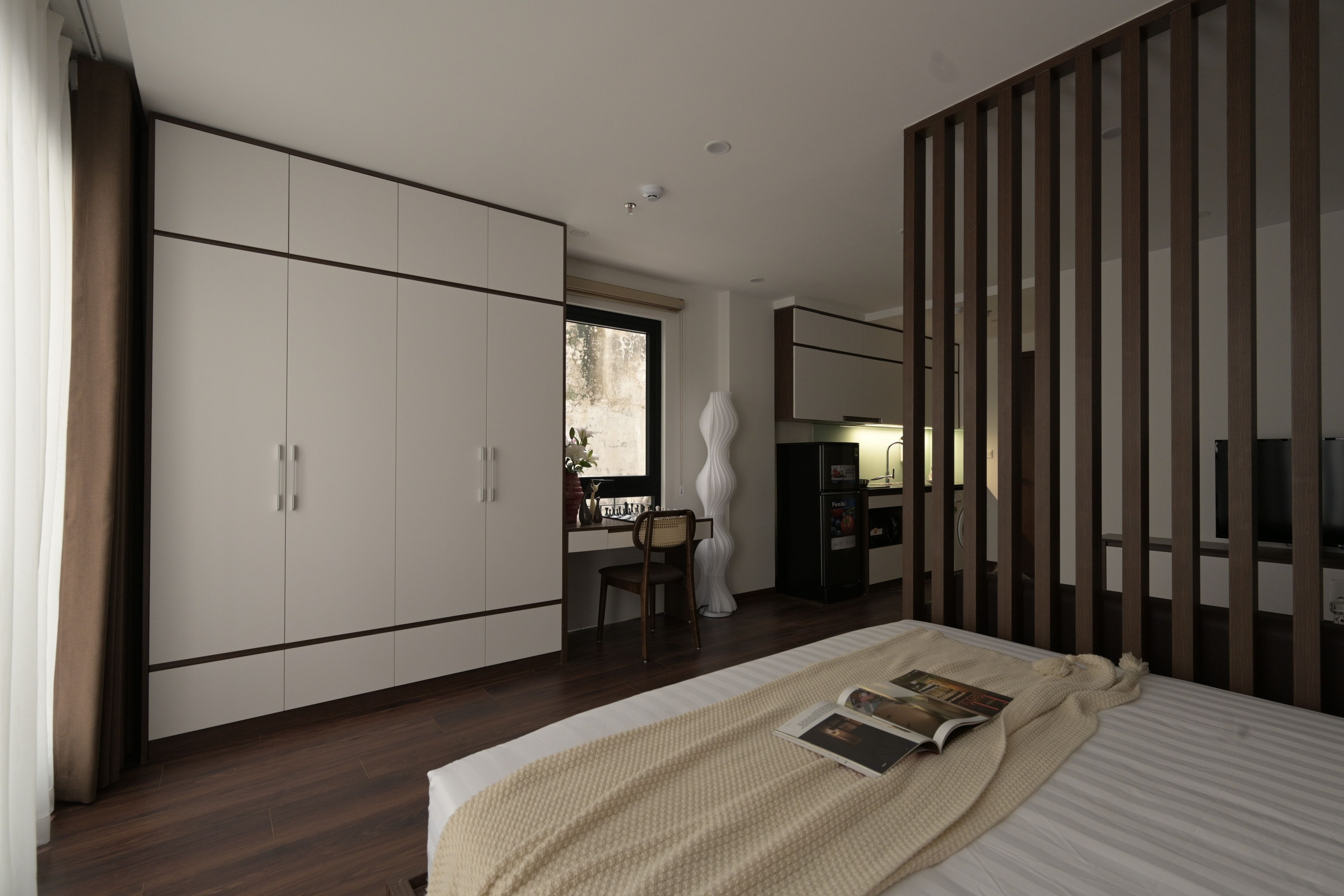 Een moderne slaapkamer met een groot bed, een garderobe, een bureau met stoel en een televisie.