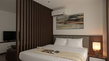 Een moderne hotelkamer met een groot bed, een flatscreen televisie, een nachtkastje met een lamp en een schilderij aan de muur.