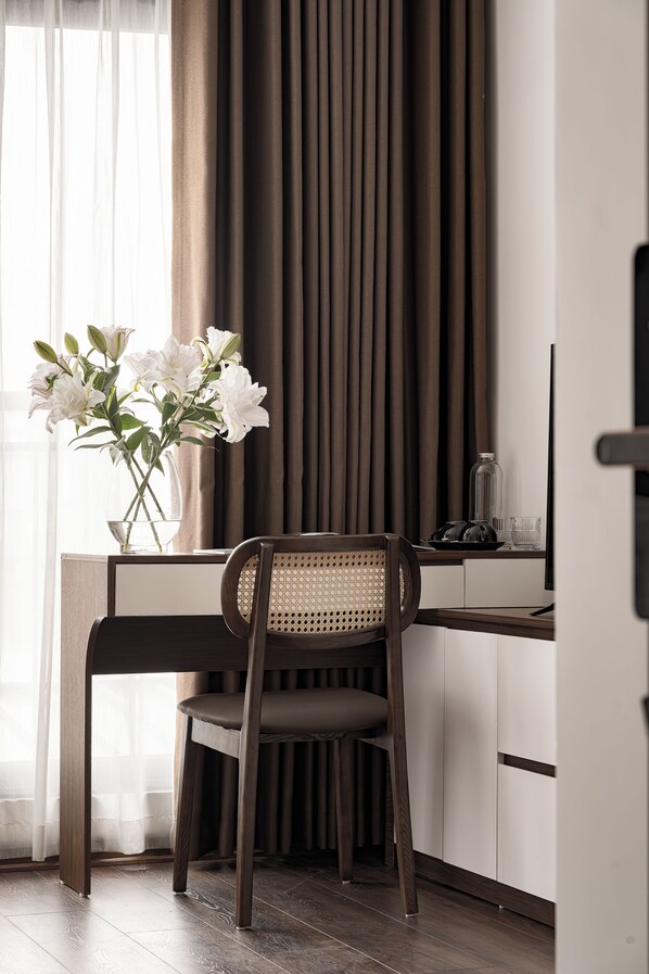 Ein modernes Zimmer mit Schreibtisch, Stuhl und einer Blumenvase.