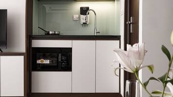 Een moderne keuken met witte kastjes, een magnetron en een spoelbak.