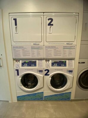 A pair of front-loading washing machines with control panels, labeled 1 and 2, in a commercial setting. - Rio with comfort and security - the perfect stay! (Rio de Janeiro)