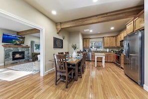 Una cocina moderna con armarios de madera, un refrigerador de acero inoxidable y una zona de comedor con mesa y sillas de madera.