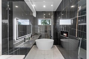 Un baño moderno con una bañera grande, un espejo y una ventana.