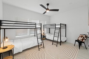 Ein Zimmer mit Etagenbetten, einem Deckenventilator und einem gemusterten Teppich.