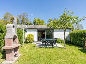 A house with a patio, a stone sculpture, and a garden. - Holiday Apartment With 2 Bedrooms (Burgh-Haamstede)