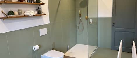 A bathroom with a shower, two sinks, a toilet, and a door.