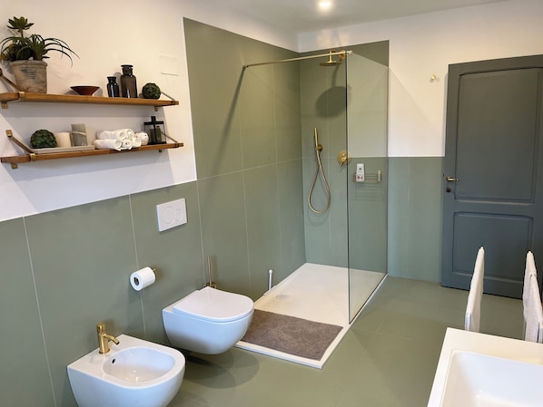 Un baño con ducha, dos lavamanos, un inodoro y una puerta.