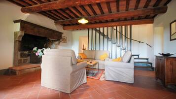 Una sala de estar acogedora con chimenea, un conjunto de sofás y una escalera.