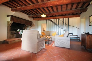 Una sala de estar acogedora con chimenea, un conjunto de sofás y una escalera.