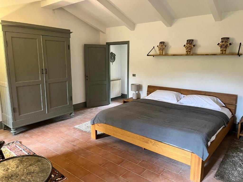 A bedroom with a wooden bed, a wardrobe, and a shelf with decorative items.