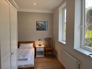 A bedroom with a bed, a nightstand, a chair, a window, and a painting on the wall. - Holiday Home With 4 Bedrooms (Braunlage)