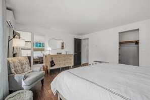 A bedroom with a bed, a dresser, a chair, a mirror, and a wardrobe. - Cozy River Retreat on Deschutes: Hot Tub, Dog Friendly, Game Room + Quality Beds (Three Rivers)