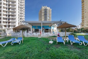 A hotel with outdoor seating and a pool area. - Apartment 'Camões 12 Frente Mar' with Shared Pool and Balcony (Armação de Pêra)