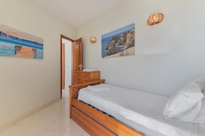 A bedroom with a wooden bed, a nightstand, a dresser, and two wall-mounted lamps. - Apartment 'Camões 12 Frente Mar' with Shared Pool and Balcony (Armação de Pêra)