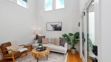 A modern living room with a sofa, coffee table, and a large plant.