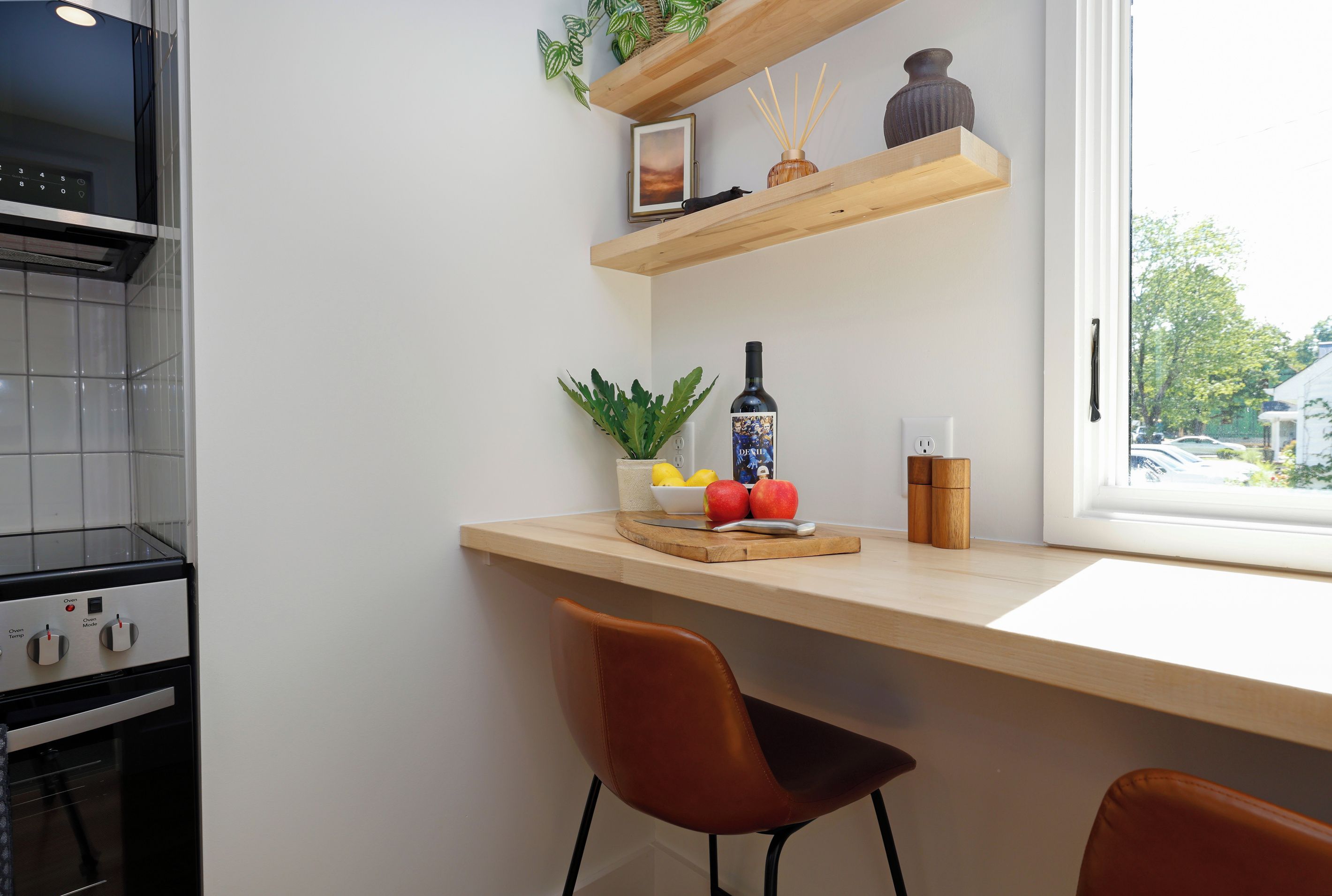 A kitchen with a built-in oven, a wooden countertop, and a window with a view of the outside.
