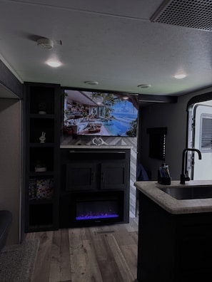 A modern kitchen with a built-in fireplace, a sink, and a view of a pool and outdoor area.
