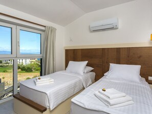 Ein Hotelzimmer mit zwei Betten, einem großen Fenster und einer Klimaanlage.