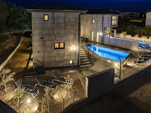 Ein modernes Gebäude mit Schwimmbad, Außenbereich und gut beleuchteter Fassade.