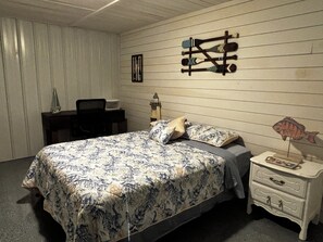 Un dormitorio con cama, mesita de noche, escritorio y un adorno en la pared.