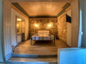 A bedroom with a stone wall, a bed, and a wooden ceiling. - Hotel Apsis (Emporio)